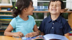 Two delighted kids enjoying a book at school. You may also like: