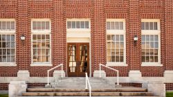 Old brick high school, post office, factory, warehouse, or office building.   No people.  Front view of entrance.