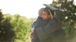 African American Father hugging his son graduation day