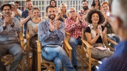 Crowd of happy freelancers congratulating public speaker on great business seminar in a board room.