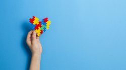 Kid hand holding multicolored heart on blue background. World autism awareness day concept