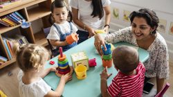 Nursery children playing with teacher in the classroom